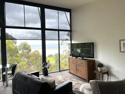 ein Wohnzimmer mit einem TV und einem großen Fenster in der Unterkunft Cloud Nine Apartment @ Tamar Ridge in Grindelwald