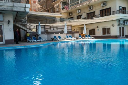 a large blue swimming pool with chairs and umbrellas at AIFU Hotel El Montazah Alexandria in Alexandria