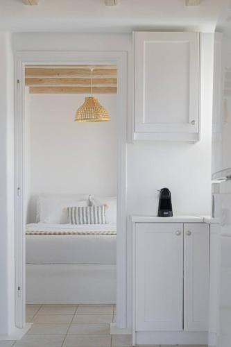 a white room with a bed and a kitchen at Koumi Homes Mykonos in Elia