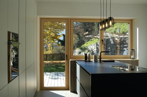 eine Küche mit einem großen Fenster und einer schwarzen Arbeitsplatte in der Unterkunft Villa Vitis in Riffian