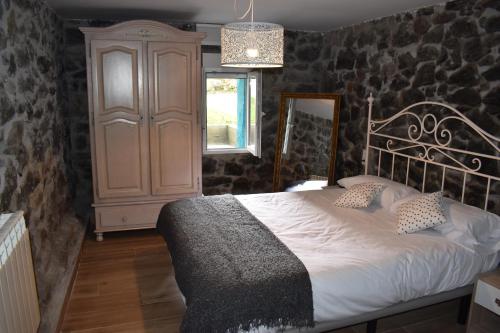a bedroom with a bed with a stone wall at LA CASA AZUL, un oasis de calma, vistas impresionantes con PISCINA, SALTADOR, BARBACOA y acceso al río Asón in Ramales de la Victoria