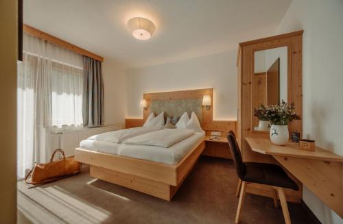 a bedroom with a bed and a desk and a mirror at Rohrmooser Schlössl in Schladming