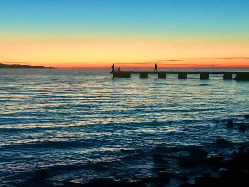 a view of the ocean with a pier at sunset at VILLA mandala in Ankaran