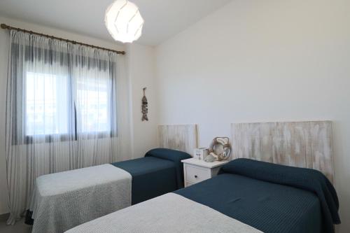 - une chambre avec 2 lits et une fenêtre dans l'établissement Apartamento Familiar La Reserva, à El Rompido