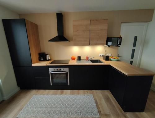 een keuken met zwarte kasten en een aanrecht bij Nouveau T2 en face du lac - Meublé tourisme - Garage privé in Évian-les-Bains