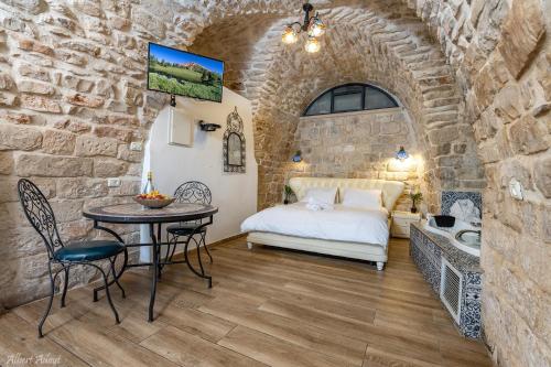 um quarto com uma cama e uma mesa numa parede de pedra em Heart Mansion Rashbi compound em Safed