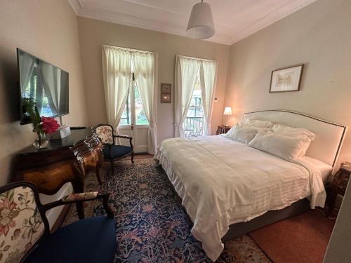 a bedroom with a large white bed and two windows at Rowan Brae Historic Guesthouse in Blackheath