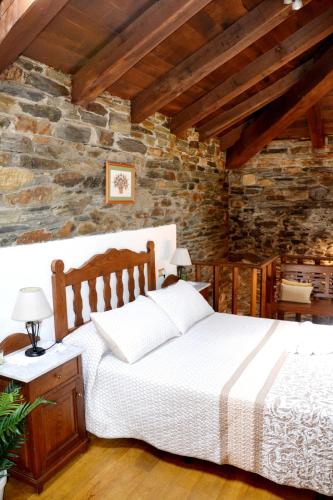 a bedroom with a bed and a stone wall at Apartamentos Rurales RON in Ron