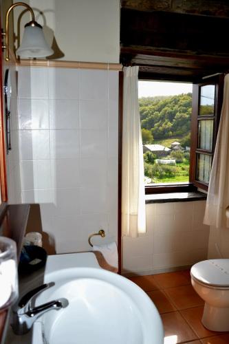 a bathroom with a sink and a toilet and a window at Apartamentos Rurales RON in Ron