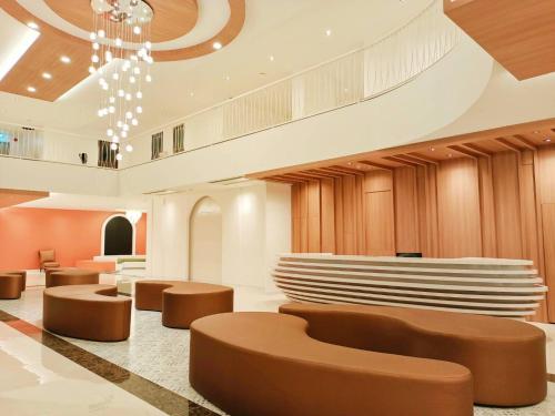 a lobby with brown seating and a chandelier at M CASA HOTEL PATTAYA in Nong Prue