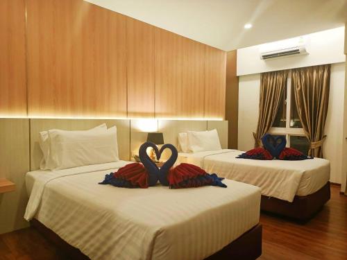 two beds with swans on them in a hotel room at M CASA HOTEL PATTAYA in Nong Prue
