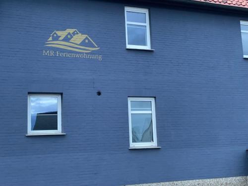 een blauw gebouw met ramen en een bord erop bij MR Ferienwohnung - Einzelzimmer Lina in Schellerten