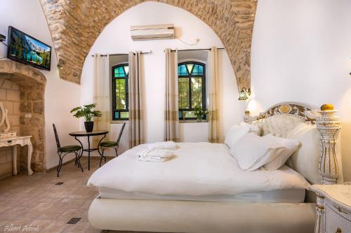 1 dormitorio con 1 cama blanca, mesa y sillas en The Antiquity Heart Mansion, en Safed
