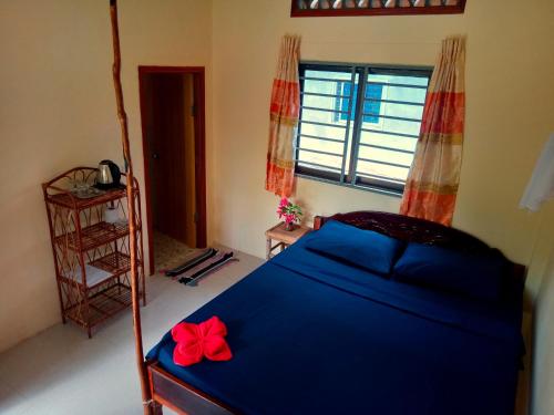 ein Schlafzimmer mit einem blauen Bett mit einer roten Schleife darauf in der Unterkunft Baloo Guesthouse in Koh Rong Sanloem