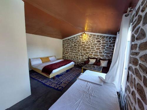 - une chambre avec un lit et un mur en pierre dans l'établissement HimWanderer Camps & Cottages Pangot, à Nainital