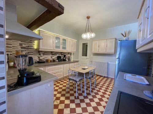 a kitchen with white cabinets and a checkered floor at Gite L'Instant Champenois in Bréviandes