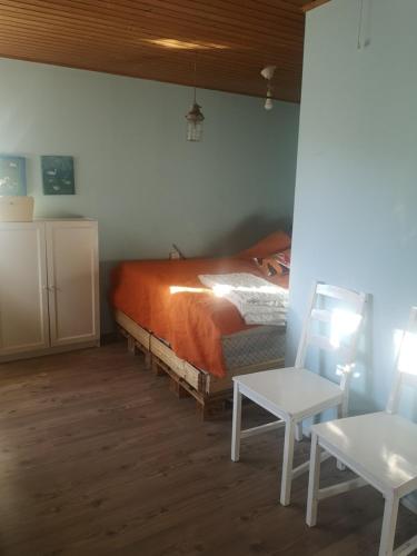 1 dormitorio con 1 cama con manta naranja y mesa en Mummon saunamökki en Helsinki