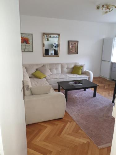 un soggiorno con un divano bianco e un tavolo di apartman oli a Sarajevo