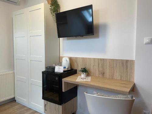 a room with a desk and a tv on a wall at Airport Almáskert Panzió in Vecsés