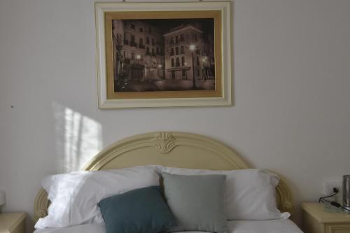 a painting above a bed with pillows on it at La casa di Nonno in Iglesias