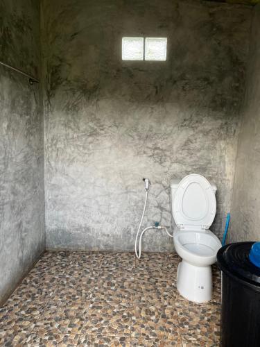 a bathroom with a toilet in a stone wall at Rak Suan Homestay รักสวนโฮมสเตย์ in Khao Lak