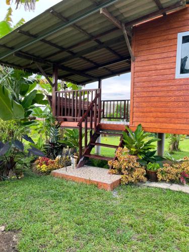 a wooden pergola with a wooden staircase in a yard at Rak Suan Homestay รักสวนโฮมสเตย์ in Khao Lak