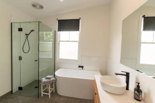 La salle de bains est pourvue d'une baignoire, d'un lavabo et d'une douche. dans l'établissement Newly renovated, Kennedy Cottage - close to CBD, à Bendigo