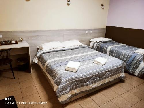 two beds in a hotel room with towels on them at Hotel Emmy in Milan