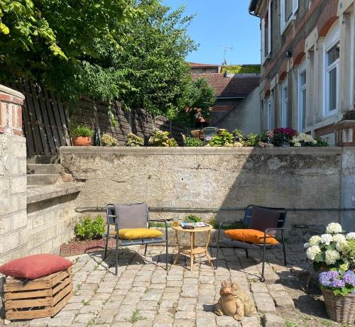 a patio with three chairs and a table with a cat on it at Le Clos maison 3 chambres avec extérieur et parking Epernay centre in Épernay