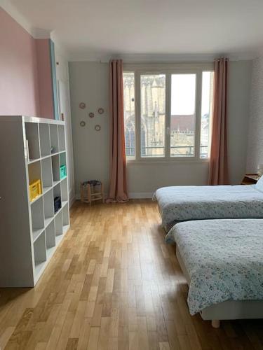 une chambre avec deux lits et une grande fenêtre dans l'établissement Appart 90m2 lumineux, centre, vue église penchée, à Caen