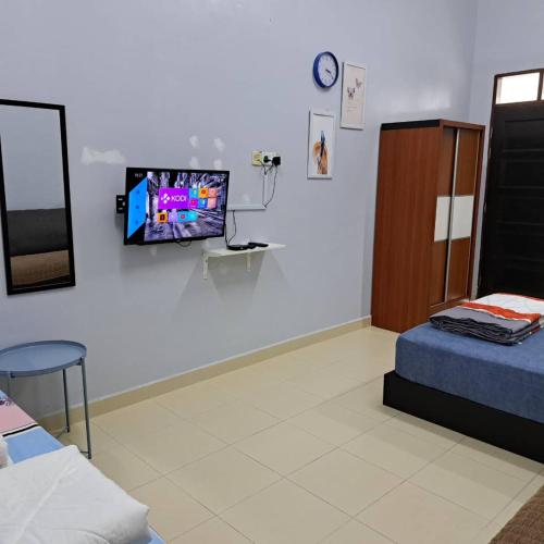 Avohomestay YouTube Netflix في كوالا ترغكانو: غرفة بها سرير وتلفزيون على الحائط
