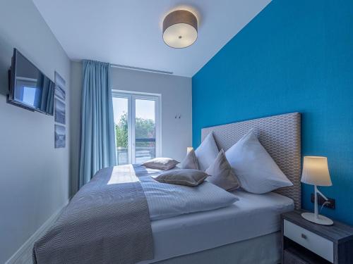 - une chambre avec des murs bleus et un lit avec des oreillers dans l'établissement Achterndieck in der Alten Seefahrtschule, à Wustrow