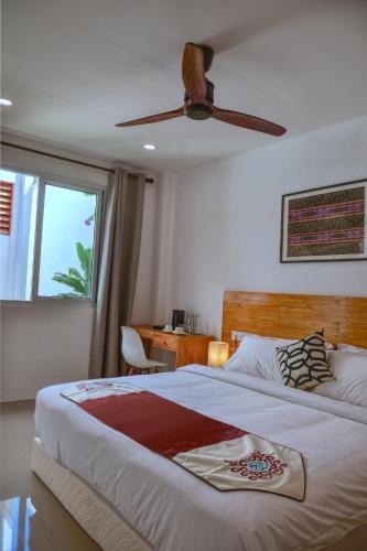a bedroom with a large bed with a ceiling fan at Island Ambience in Maafushi