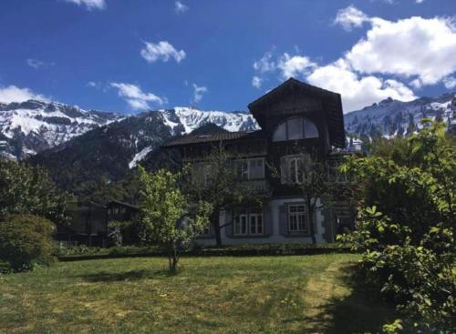 une grande maison avec des montagnes en arrière-plan dans l'établissement Chalet Mignon - your vacation oasis at Lake Brienz, à Bönigen