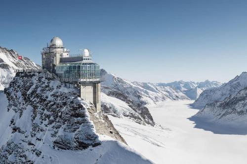a building on the side of a snowy mountain at Chalet Mignon - your vacation oasis at Lake Brienz in Bönigen