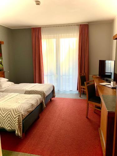 a hotel room with two beds and a desk at Hotel Szarlota - Kompleksowo na Kaszubach in Kościerzyna