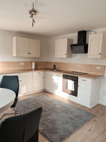 a kitchen with white cabinets and a table and a rug at Gemütliche Wohnung in Bleckede an der Elbe in Bleckede