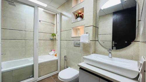 BluO Studio Noida - BathTub, Gym, Balcony, Garden في نويدا: حمام مع حوض ومرحاض ومرآة