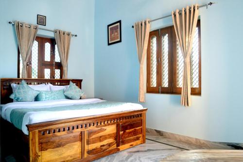 a bedroom with a bed with blue walls and windows at Hotelier Hosts - A Home Stay in Jodhpur