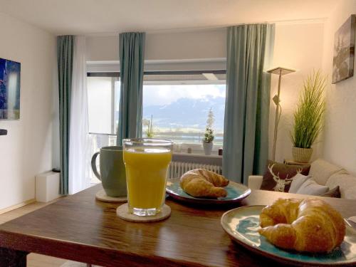 un tavolo con un bicchiere di succo d'arancia e croissant di Moderne, 1-Zimmer Ferienwohnung mit Bergblick a Oy-Mittelberg