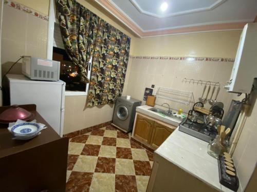 uma cozinha com piso em xadrez e um frigorífico em coop auberge trt em Taourirt