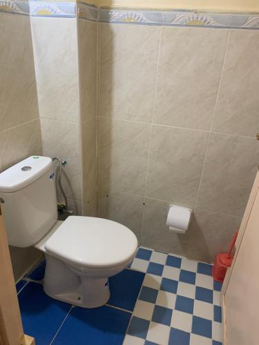 uma casa de banho com um WC e um piso xadrez azul e branco em coop auberge trt em Taourirt