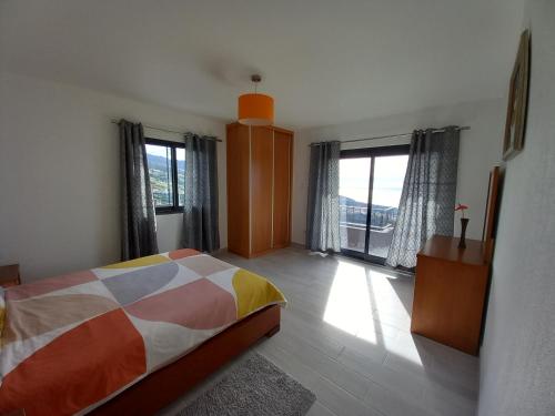 ein Schlafzimmer mit einem Bett und einem großen Fenster in der Unterkunft Casa dos Avós Domingos & Matilde in Estreito da Calheta