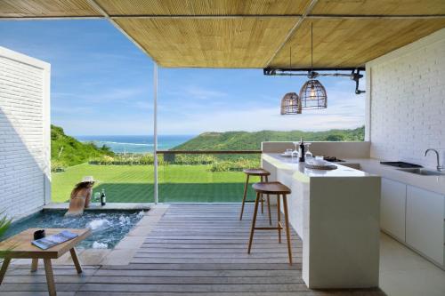 a kitchen with a pool and a view of the ocean at Telescope Resort Lombok in Kuta Lombok