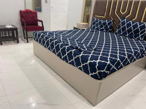 a bed with a blue and white comforter and a red chair at Gulshan Guest House Gulberg Town in Karachi