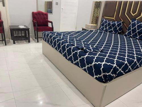 a bed with a blue and white comforter in a room at Gulshan Guest House Gulberg Town in Karachi