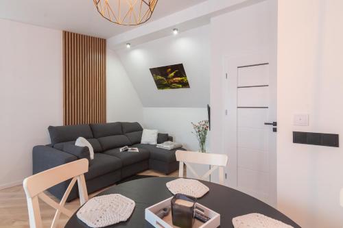 ein Wohnzimmer mit einem Sofa, einem Tisch und Stühlen in der Unterkunft Apartament Z widokiem na las in Witów