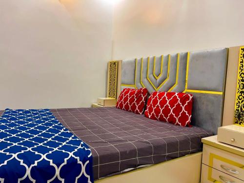 - une chambre avec un lit et 2 oreillers rouges dans l'établissement Gulshan Guest House Karachi, à Karachi