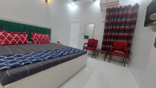 - une chambre avec un lit et deux chaises rouges dans l'établissement Gulshan Guest House Karachi, à Karachi