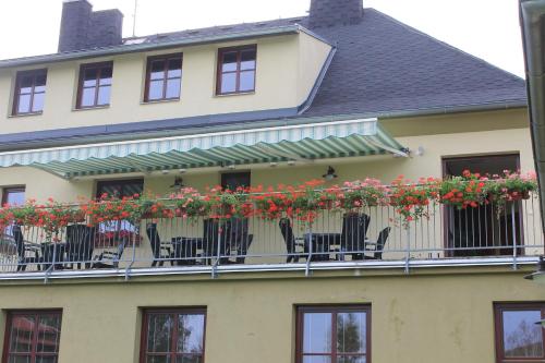 a house with chairs and flowers on the balcony at Penzion Fialka in Velké Losiny
